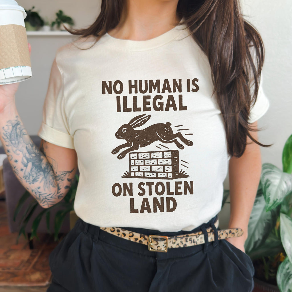 No Human Is Illegal T‑ graphic shirt featuring Social Justice Immigration Message in Daisy