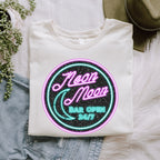 Neon Moon graphic shirt featuring 'Neon Moon Bar Open 24/7' Retro Neon Sign in Deep Teal