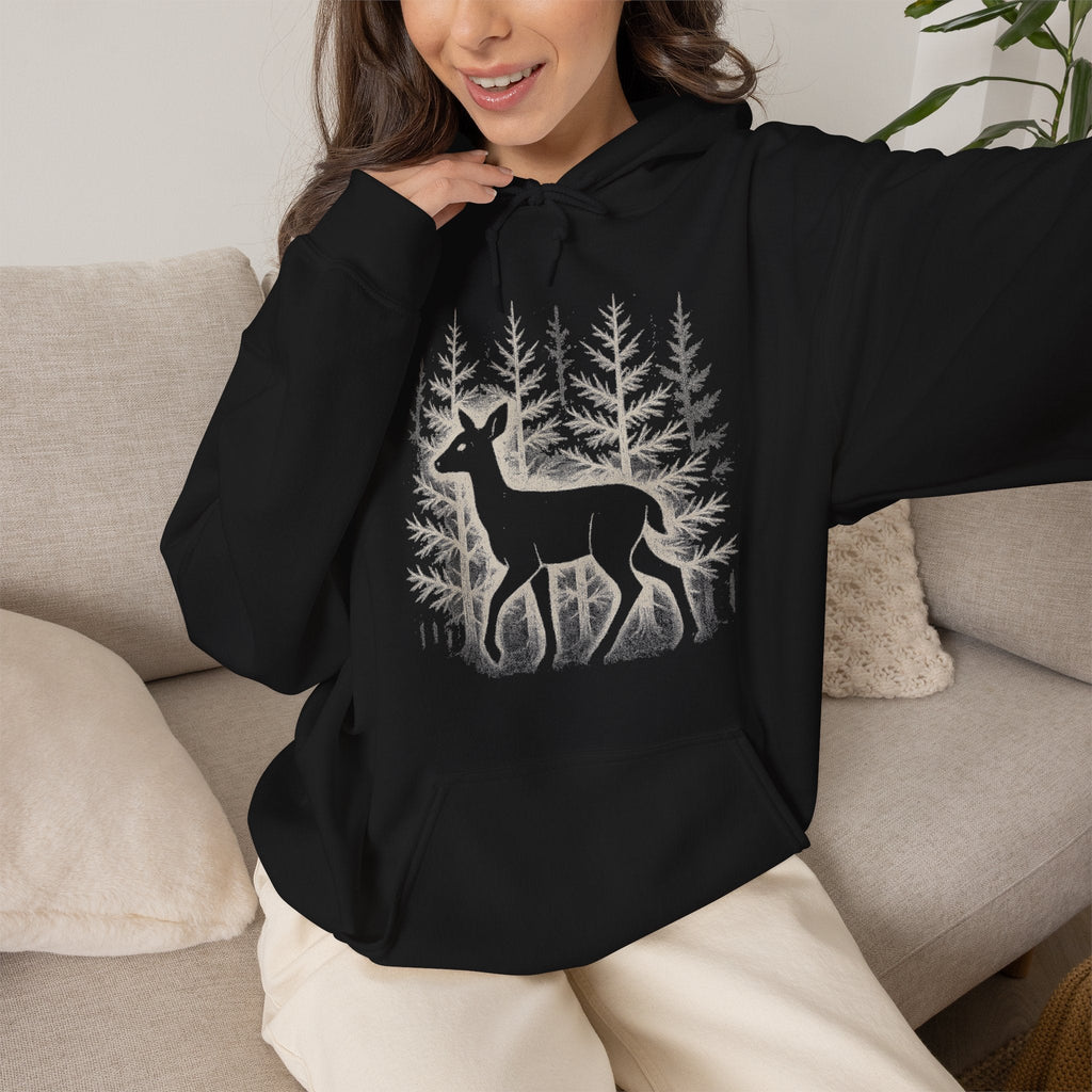 The Faithful Familiar black pullover hoodie featuring a white deer and forest silhouette graphic, worn by a woman.