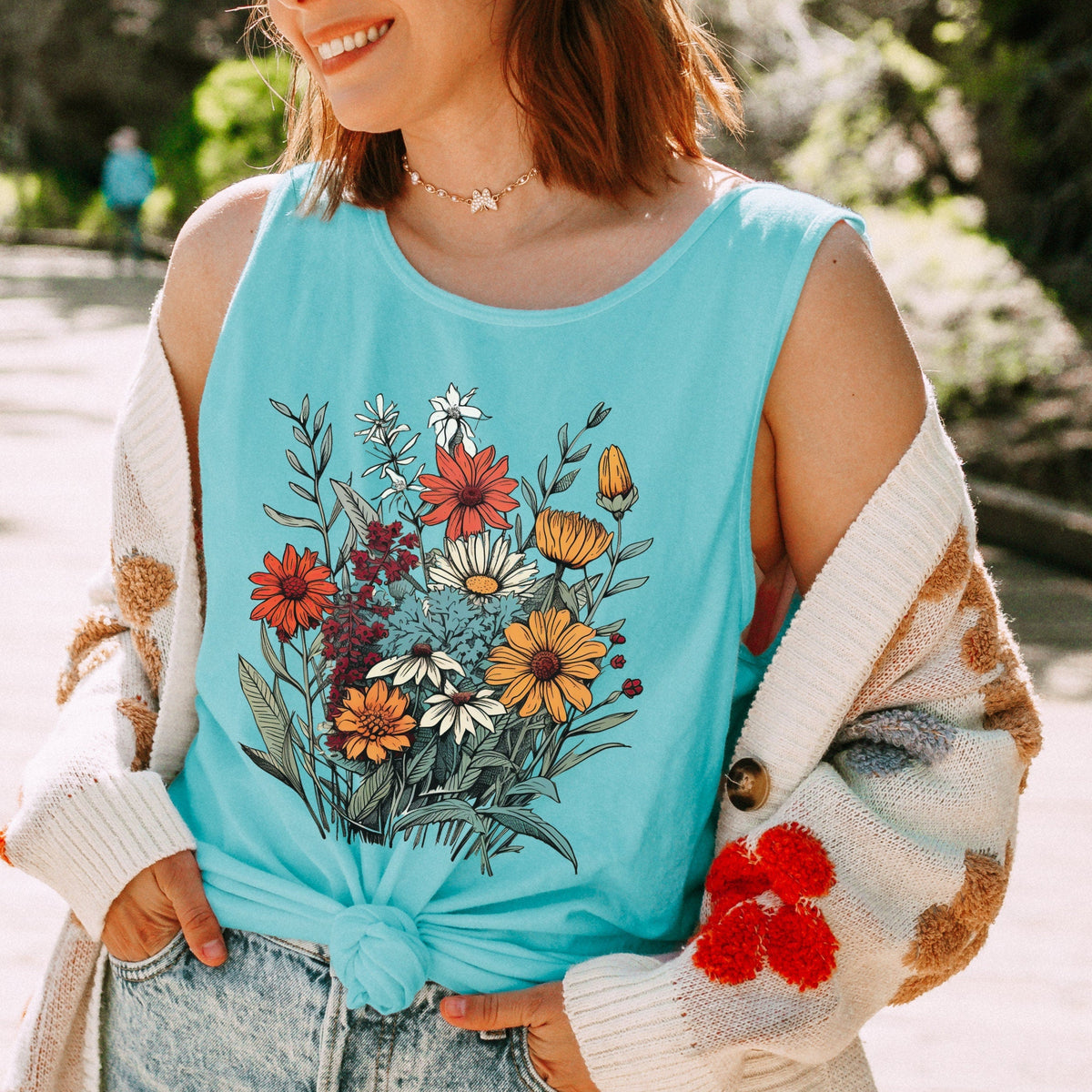 The Faithful Familiar light blue slouchy boho tank top with a vintage wildflower graphic, worn with a knit cardigan.