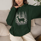 The Faithful Familiar forest green pullover hoodie featuring a white deer silhouette graphic in a snowy pine forest.