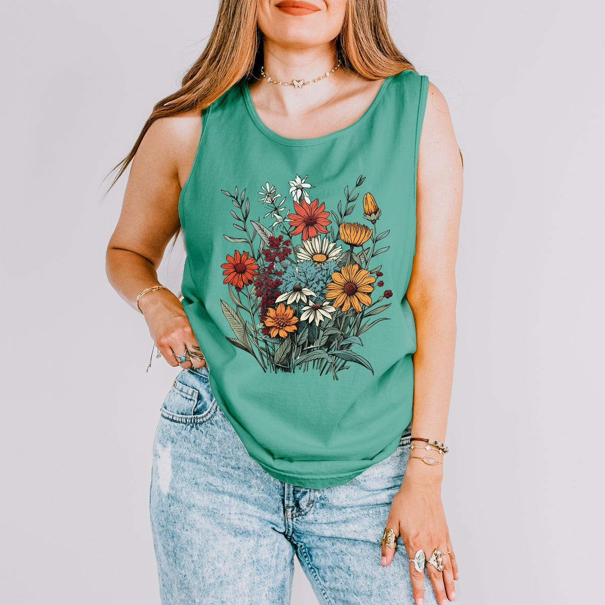 The Faithful Familiar green slouchy boho tank top with a vintage wildflower graphic worn by a woman with jeans.