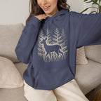 The Faithful Familiar navy blue pullover hoodie featuring a white deer and forest graphic, worn by a smiling woman.
