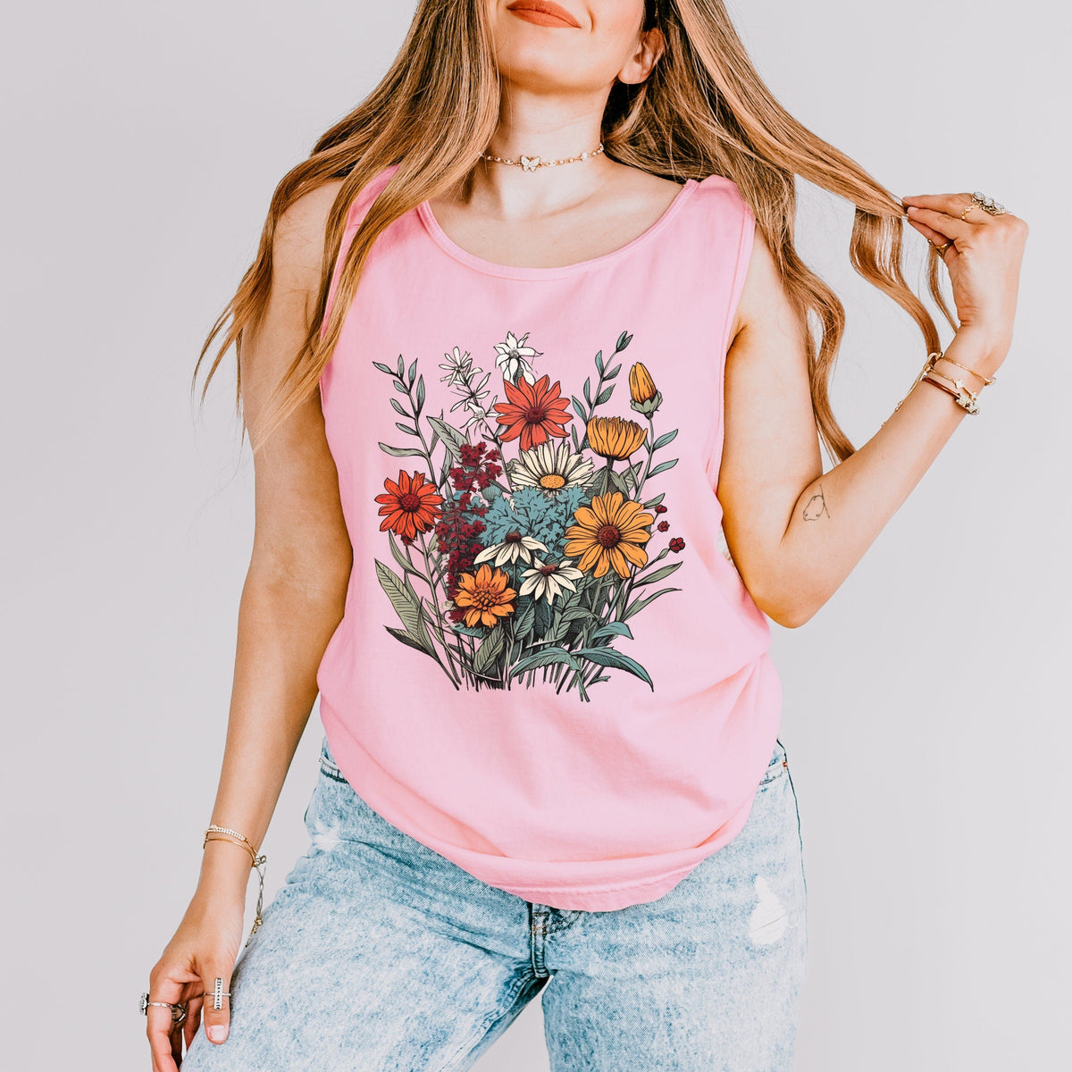 The Faithful Familiar pink slouchy boho tank top with a vintage wildflower graphic, worn by a woman with long hair.