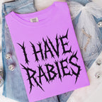 The Faithful Familiar purple Comfort Colors graphic tee with black spiky metal-style text reading I HAVE RABIES.