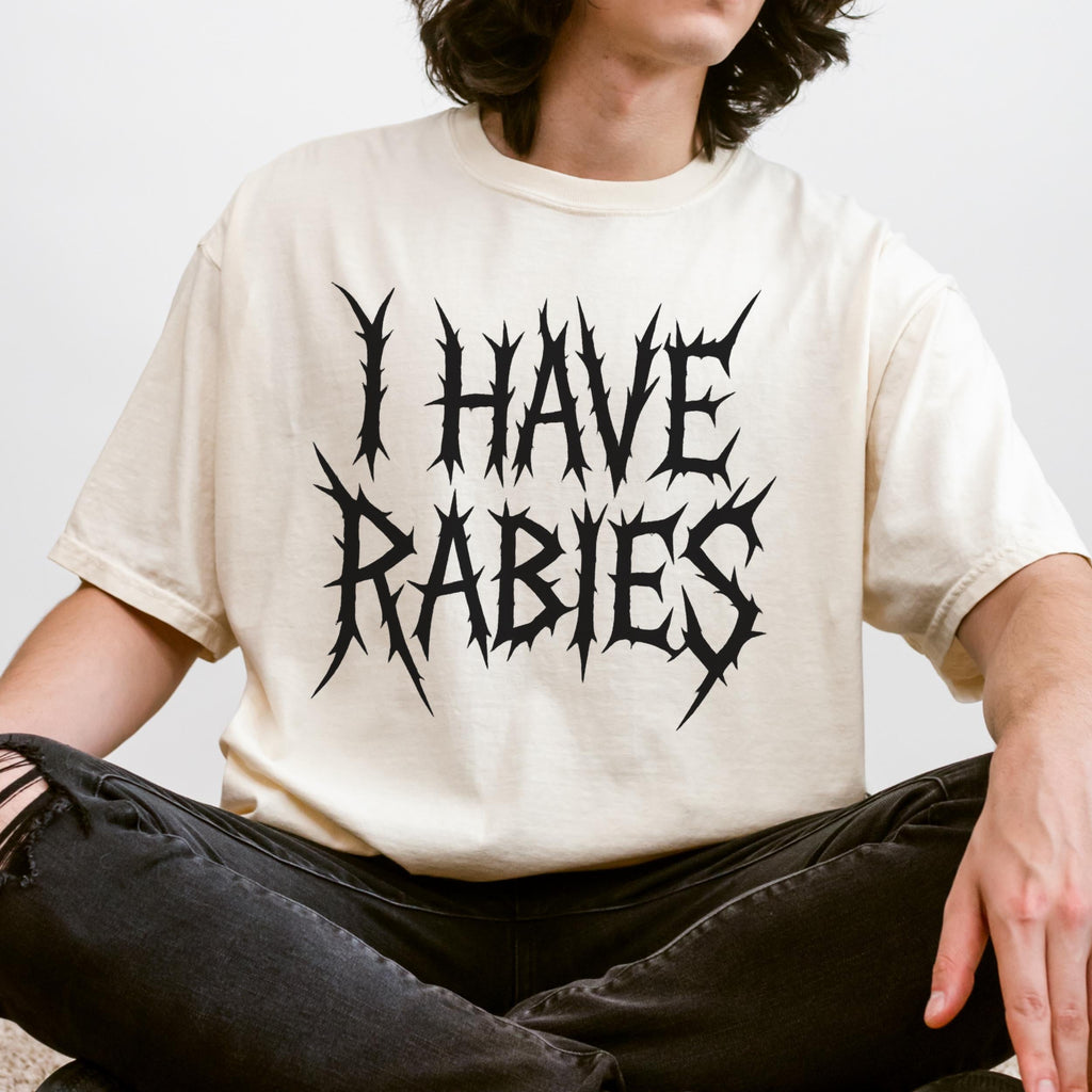 The Faithful Familiar cream Comfort Colors t-shirt with black metal-style I HAVE RABIES text worn by a person.