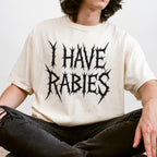 The Faithful Familiar cream Comfort Colors t-shirt with black metal-style I HAVE RABIES text worn by a person.