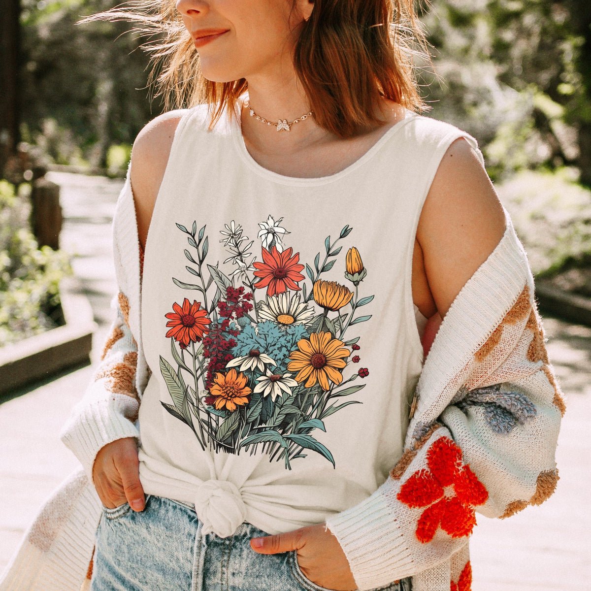 The Faithful Familiar vintage wildflower graphic tank top in cream, worn by a woman with a layered cardigan.